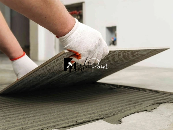 Tile fixing process, showing the placement of a tile onto a bed of adhesive using a notched trowel.