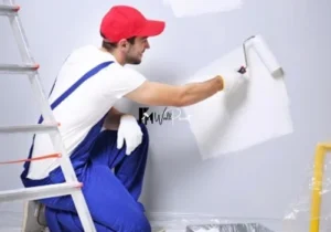 The process of house painting Dubai, showing a painter using a roller to apply a fresh coat of white paint.